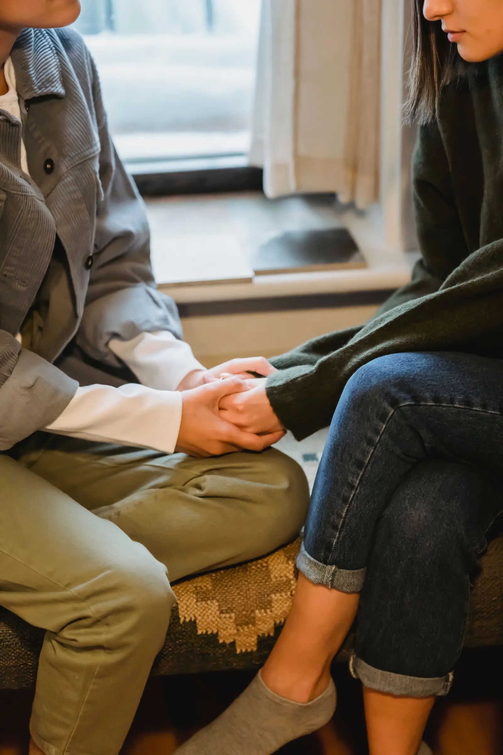 A team member sitting alongside an adult, having a warm one to one conversation in a bright community space